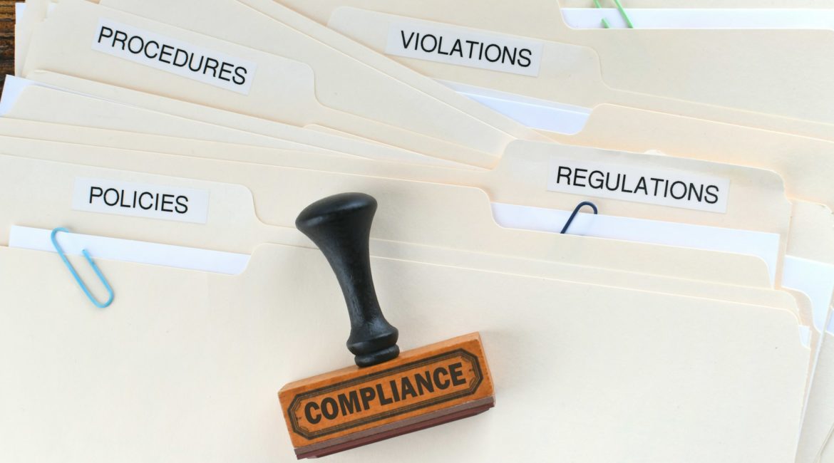 Compliance rubber stamp on folders marked Policies Regulations Violations Procedures Documentation.